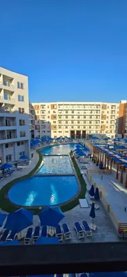 a large swimming pool with blue umbrellas and chairs at Tiba Golden Red Sea Coral Hurghada in Hurghada