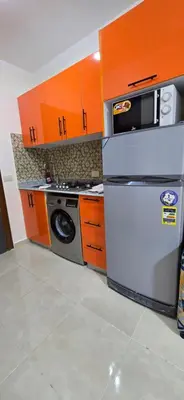 a kitchen with orange cabinets and a white refrigerator at Tiba Golden White Lagoon Hurghada in Hurghada