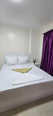 a bedroom with a white bed with a purple curtain at Tiba Golden Whire Sands Hurghada in Hurghada