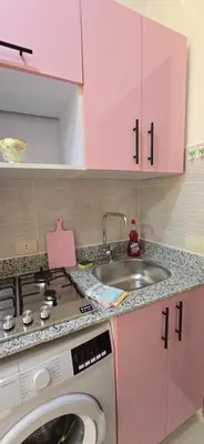 a pink kitchen with a sink and a washing machine at Tiba Golden Whire Sands Hurghada in Hurghada