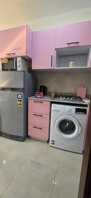 a kitchen with a washing machine and pink cabinets at Tiba Golden Whire Sands Hurghada in Hurghada