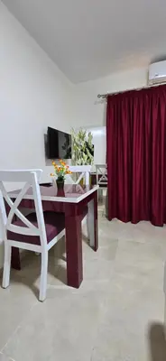 a living room with a table and a red curtain at Tiba Golden Sea Harmony Hurghada in Hurghada