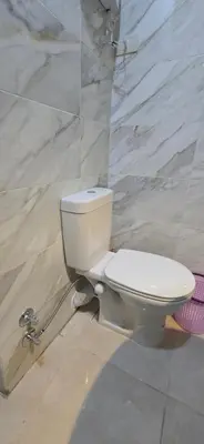 a white toilet in a bathroom with a marble wall at Tiba Golden Sea Harmony Hurghada in Hurghada