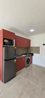 a kitchen with red cabinets and a stainless steel refrigerator at Tiba Golden Serenity Hurghada in Hurghada