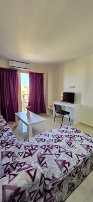 a bedroom with a bed and a table and purple curtains at Tiba Golden Sand Palace Hurghada in Hurghada