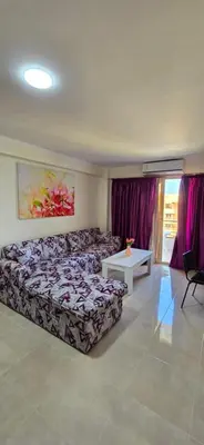 a room with two beds and a table and purple curtains at Tiba Golden Sand Palace Hurghada in Hurghada