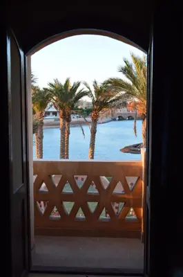 an open door with a view of the water and palm trees at El Gouna 4 Bedroom 4 Bathroom Lagoon villa in Banī Ghālib