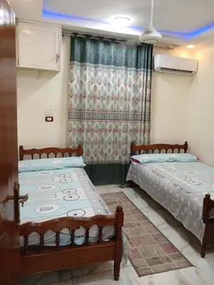 two beds in a room with a window at شقه فاخره مجهزه بالكامل مكيفه مع ثلاث غرف في وسط الاقصر in Luxor