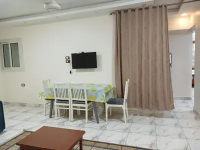 a living room with a table and chairs and a tv at شقه فاخره مجهزه بالكامل مكيفه مع ثلاث غرف في وسط الاقصر in Luxor