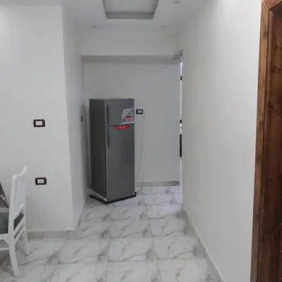 a room with a refrigerator in a white wall at شقه فاخره مجهزه بالكامل مكيفه مع ثلاث غرف في وسط الاقصر in Luxor