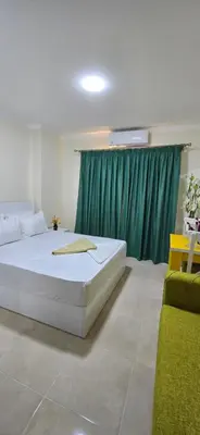 a bedroom with a large bed and a green curtain at Tiba Golden Oasis Mirage Hurghada in Hurghada
