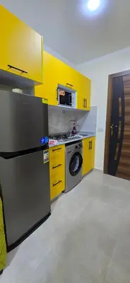 a kitchen with yellow cabinets and a stainless steel refrigerator at Tiba Golden Oasis Mirage Hurghada in Hurghada