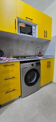 a kitchen with yellow cabinets and a washing machine at Tiba Golden Oasis Mirage Hurghada in Hurghada