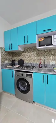a kitchen with blue cabinets and a washing machine at Tiba Golden Palm Hurghada in Hurghada