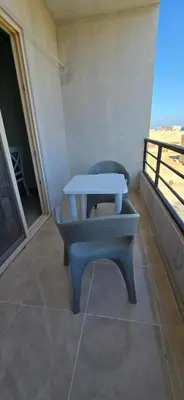 a table and a chair sitting on a balcony at Tiba Golden Palm Hurghada in Hurghada