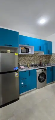 a kitchen with blue cabinets and a stainless steel refrigerator at Tiba Golden Sun flare Hurghada in Hurghada