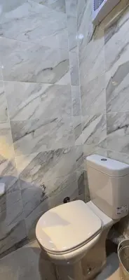 a white toilet in a bathroom with marble walls at Tiba Golden Sapphire Hurghada in Hurghada