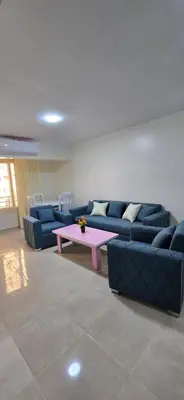 a living room with blue couches and a pink coffee table at Tiba Golden Sunset Oasis Hurghada in Hurghada