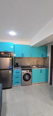 a kitchen with blue cabinets and a washing machine at Tiba Golden Sunset Oasis Hurghada in Hurghada