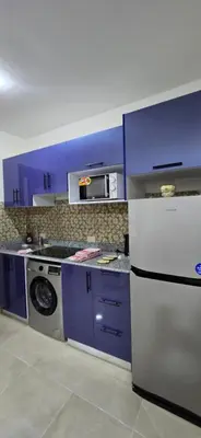 a kitchen with purple cabinets and a washer and dryer at Tiba Golden Beach View Hurghada in Hurghada