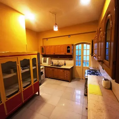 a kitchen with yellow walls and wooden cabinets at Villa Karmen in Luxor