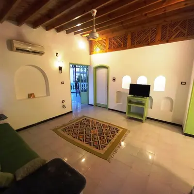 a living room with a couch and a tv and a table at Villa Karmen in Luxor