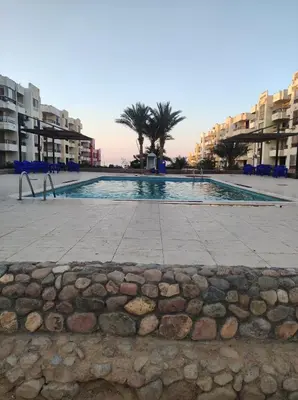 a large swimming pool with palm trees and buildings at Summer land in Hurghada