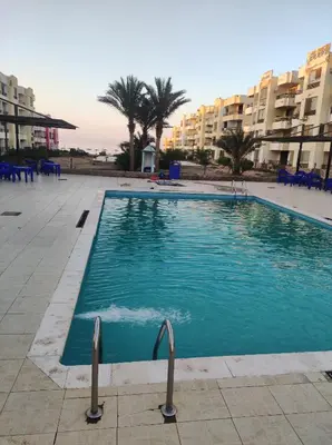 a swimming pool in a resort with palm trees and buildings at Summer land in Hurghada