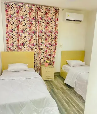 a bedroom with two beds and a curtain with flowers at El Hambra compound in Hurghada