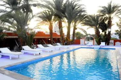 a swimming pool with white chairs and palm trees at Sun Beach Hotel ABO SOMA in Hurghada