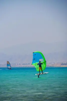a man on a surfboard with a sail on the water at Sun Beach Hotel ABO SOMA in Hurghada