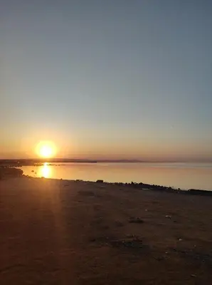 a sunset over a body of water with the sun setting at Hurghada in Hurghada
