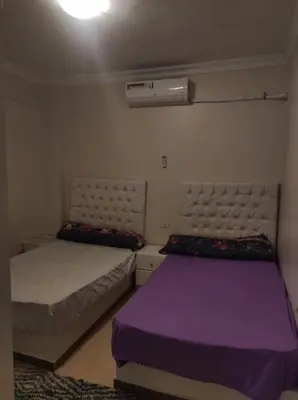 two beds in a room with purple and white at Hurghada in Hurghada