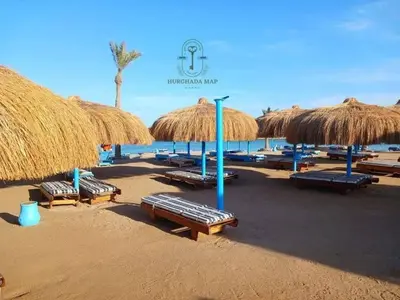 a beach with many straw umbrellas and lounge chairs at TiBa Golden Resort in Hurghada