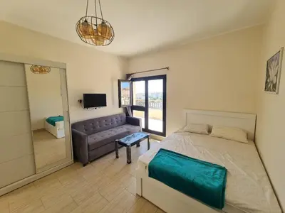 a bedroom with a bed and a couch and a television at AlDau Heights Modern Studio with Terrace, Mountain & City View in Hurghada