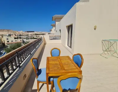 a wooden table and chairs on a balcony at AlDau Heights Modern Studio with Terrace, Mountain & City View in Hurghada