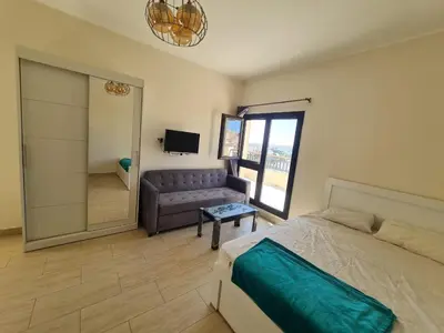 a bedroom with a bed and a couch and a mirror at AlDau Heights Modern Studio with Terrace, Mountain & City View in Hurghada