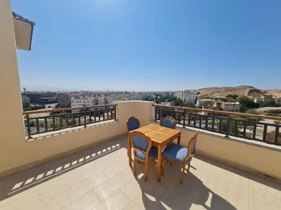 a table and chairs on a balcony with a view at AlDau Heights Modern Studio with Terrace, Mountain & City View in Hurghada