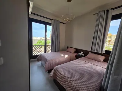 two beds in a room with a view of a balcony at Jade 18 A in Hurghada
