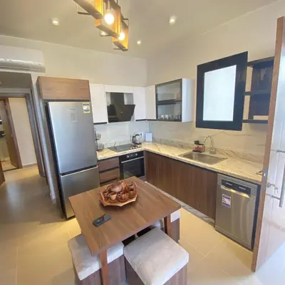 a kitchen with a wooden table and a stainless steel refrigerator at Jade 18 A in Hurghada