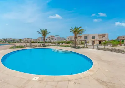 a large swimming pool with palm trees and buildings at Calm 3BR House in Shedwan Gouna BBQ, Pool & Lagoon in Hurghada