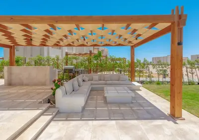 a patio with a couch under a wooden pergola at Calm 3BR House in Shedwan Gouna BBQ, Pool & Lagoon in Hurghada