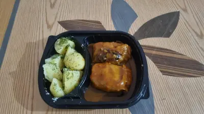 a black container of food with meat and broccoli at Orientalna Willa in Hurghada