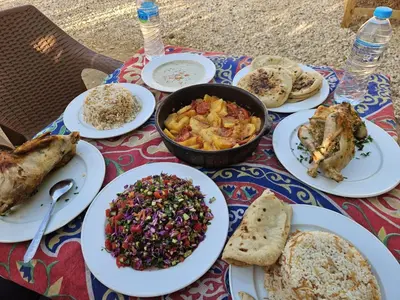 a table with plates of food on a table at Gateway to the Stars restaurant & camping in Al Aqālitah