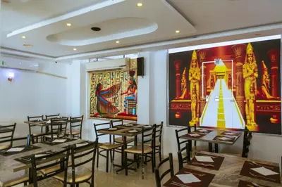 a restaurant with tables and chairs and paintings on the walls at Fox House Resort in Hurghada