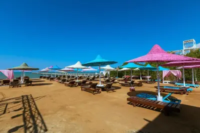 a bunch of chairs and umbrellas on a beach at Fox House Resort in Hurghada