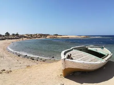 a boat sitting on a beach next to the water at hassany hotel in Hurghada