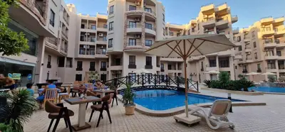 a hotel with a pool and tables and an umbrella at Pohodové bydlení v Hurghade in Hurghada