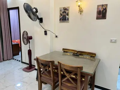 a dining room table with two chairs and a fan at شقة خلف فندق الإليزي in Hurghada