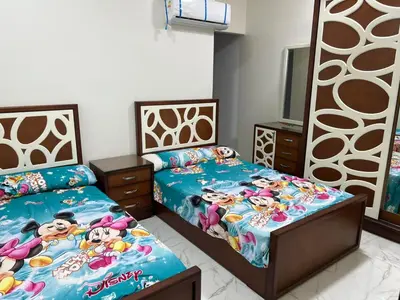 a bedroom with two twin beds and a tv at شقة خلف فندق الإليزي in Hurghada